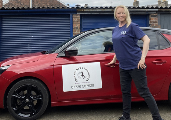 Owner of company beside red car with company logo on side